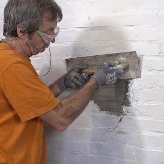 Luk hul efter brændeovn: Træk pudslaget af med et stålbræt Luk hul efter brændeovn: Træk pudslaget af med et stålbræt